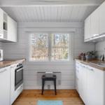 Kitchen with white cabinets, wooden countertops, and window view of trees.
