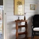A room with white wood paneling, a black chair with fur, and a wooden table.