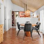 Dining area with round table and black chairs. Kitchen area with wooden ceiling and red tiles.