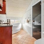 Bathroom with bathtub, sink and toilet. Passage to shower with bathtub.