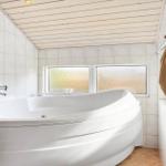 Bath with whirlpool, tiled walls, and two windows with frosted glass.