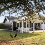 House with terrace, grill, and swing under tree.