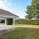 Garden with pavilion, white table and chairs, grill and large tree.