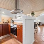 Kitchen with wooden ceiling, stainless steel stove, and terracotta floor