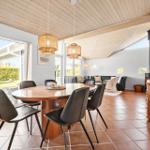 Dining area with round table and chairs. Living area with sofa and stove. Wooden ceiling and terrace door.