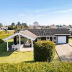 Single-story house with terrace, grill, and garage on green grounds.
