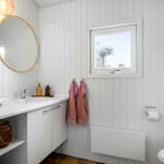 Bathroom with sink, mirror, and toilet. Window and towels visible.