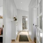 Hallway with white walls, wooden floor, and cabinet. Passage to the shower.