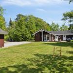 A house with a garden, terrace, and play equipment. Surrounded by trees and grass.
