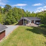 A house with terrace and garden surrounded by trees under blue sky.