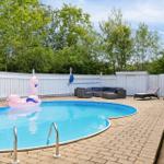 Pool with pink flamingo, lounge area, and wooden house in background.