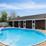 Pool with pink flamingo, terrace, and wooden house in background.