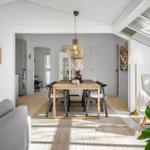 Living and dining area with wooden table, seating, and skylights.
