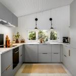 Modern kitchen with gray cabinets, marble countertop, and window with view of trees.