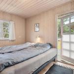 Schlafzimmer mit Holzwand, Bett und Tür zum Außenbereich.