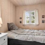 Schlafzimmer mit Holzwand, Bett, Nachttisch und Fenster.