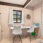 Wohnraum mit Schreibtisch, zwei Stühlen und Fenster mit weißen Vorhängen.