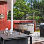 Terrasse mit Esstisch, Grill und Whirlpool. Dartboard an der Wand.
