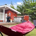 Roter Hängematte auf Gras vor rotem Haus mit Terrasse und Grill.