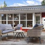 Terrasse mit Sitzgruppe und Tisch vor rotem Haus mit Fensterfront