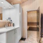 Badezimmer mit Dusche und Sauna. Weiße Waschbecken und Holzwände.