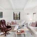 Wohnzimmer mit weißen Wänden, Sofa, braunem Sessel und Tisch.