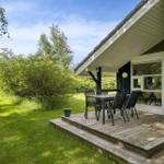 Terrasse mit Tisch und Stühlen vor einem Haus mit Holzveranda und grünem Garten.