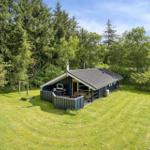 Hütte mit Terrasse, Grill und Schaukel im grünen Garten.