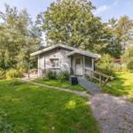 Ein kleines Haus mit weißen Wänden, einem Eingang und einem Gartenweg.
