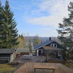 Haus mit Holzterrasse, Grillplatz und Blick auf Wald und Berge.
