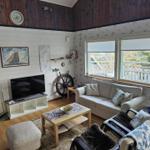 Wohnzimmer mit Sofa, Fernseher und Blick auf Balkon.