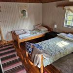 Zwei Betten, Fenster, Holzboden und Wandverkleidung in einem Schlafzimmer.