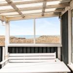 Terrasse mit weißem Tisch und Bank, Blick auf Strand und Meer.