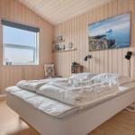 Bedroom with wooden walls, bed, and window. Wall art shows coastal landscape.