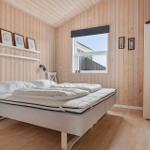 Bedroom with wooden walls, bed, and window