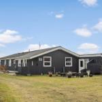 Black house with white trim and outdoor terrace under blue sky.