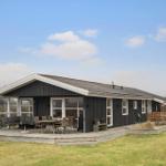 A house with dark cladding and wooden terrace. Outdoor seating is available.