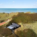 Schwarzes Haus mit Solarium auf Dünen, Blick auf das Meer.
