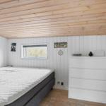 Schlafzimmer mit Bett, Kleiderschrank und Fenster. Holzdecke und weiße Wände.