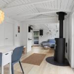 Wohnraum mit Esstisch, Kamin und Sofa. Weiße Wände, Holzboden und große Fenster.