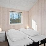 Bedroom with two beds, wooden walls, and window with view of trees.