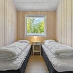 Two beds with white covers are in a room with wooden walls and a window.