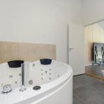 Bathroom with whirlpool tub, toilet, and door to adjacent room.