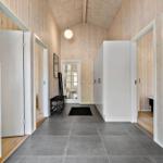 Long hallway with wooden wall cladding and gray floor tiles.