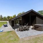 Modern wooden house with terrace, hot tub, and garden.