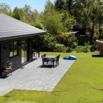House with terrace, garden, and wooden shed. Table and chairs are outside.