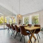 Dining room with wooden table, brown chairs, and large windows to the outdoor terrace.