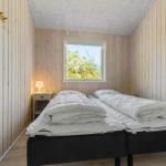 Room with two beds, wooden walls, and window with view of trees.