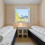 Two beds with white bedding are in a wooden room with a window.