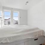 Bedroom with bed, windows, and mirror on the wall.